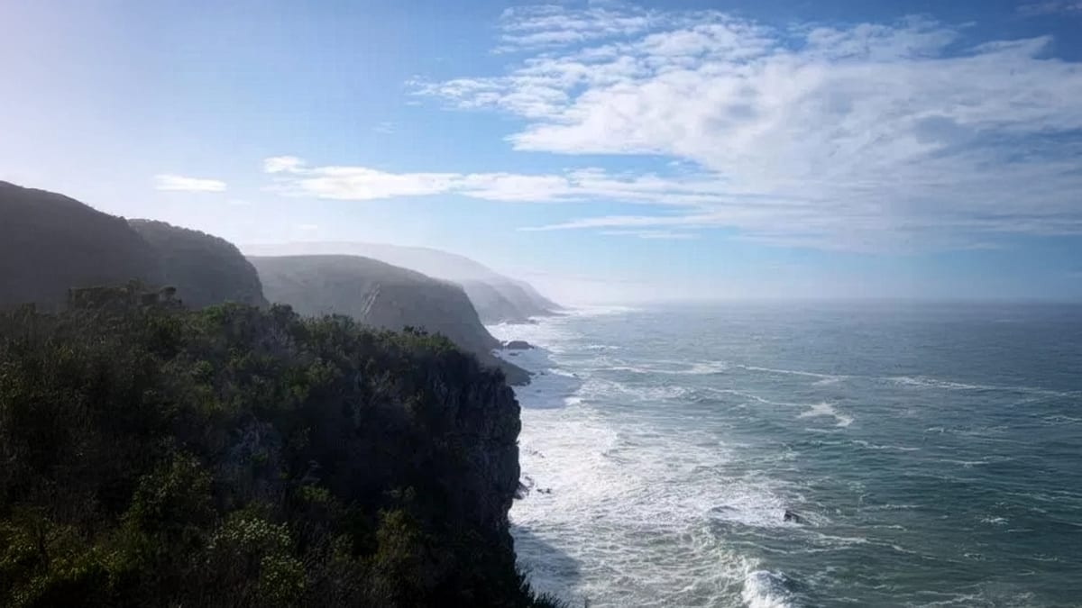 A scenic view of the ocean from a high cliff, showcasing waves crashing against the rocks below.